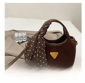 Gros plan du sac seau marron mat avec un foulard en soie à pois élégant sur la poignée