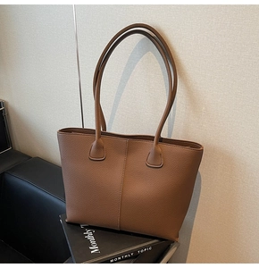 Close-up of brown pebbled leather tote bag with elegant center seam and thin shoulder straps
