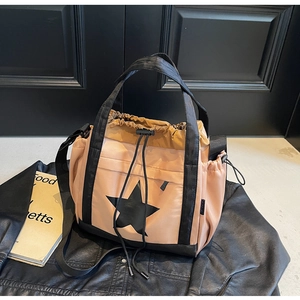 Dettaglio della borsa tote in nylon beige con motivo a stella nera e chiusura a coulisse