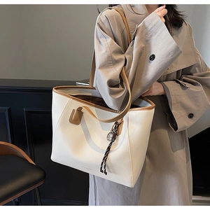Detail of the large tote bag showing white lychee leather and brown contrast straps