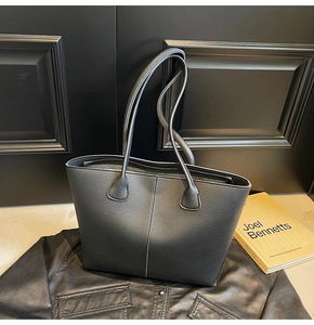Close-up of black lychee grain leather tote bag with fine vertical stitching detail