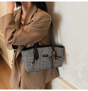 Nahaufnahme der Hahnentritt-Tasche mit Ledergriffen und Quasten-Detail am Model
