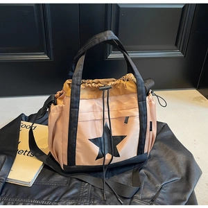 Dettaglio di una borsa tote in nylon con stampa a stella e coulisse su pelle nera