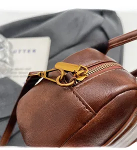 Close-up of vintage gold zipper and dark brown lychee leather texture on women's bag