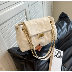 Detailed close-up of quilted white leather texture and gold chain strap of the handbag