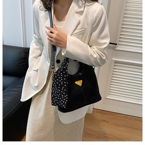 Détail du sac seau en daim noir avec logo triangle doré et anse ornée d'un foulard à pois