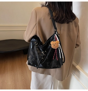 Large black shoulder bag with teddy bear charm shown from back on a model