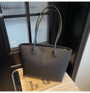 Close-up of black lychee texture tote bag with vertical stitching on stone table