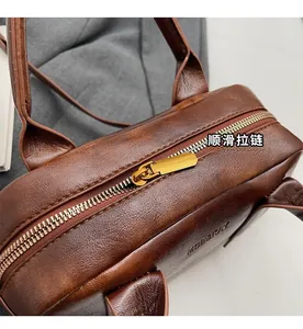 Close-up of brown textured leather handbag featuring a smooth gold metal zipper detail