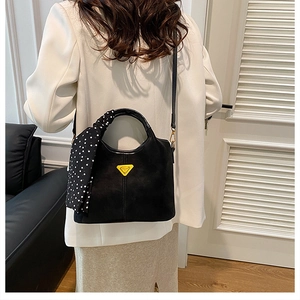 Détail du sac à main vintage noir mat avec logo jaune et foulard à pois élégant