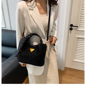 Détail du sac seau noir mat vintage avec foulard à pois sur la poignée