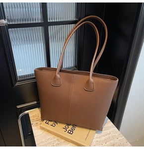 Macro shot of dark brown tote bag showing pebbled leather texture and stitching