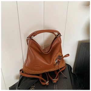 Detalle de bolso tote de cuero caramelo con borde de piel sintética y logo grabado