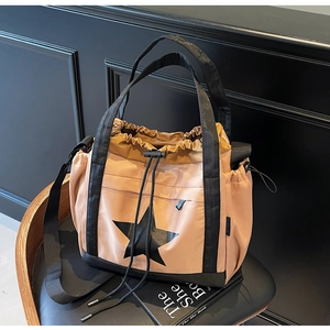 Dettaglio della borsa tote color kaki con chiusura a cordoncino e stella nera su fondo scuro