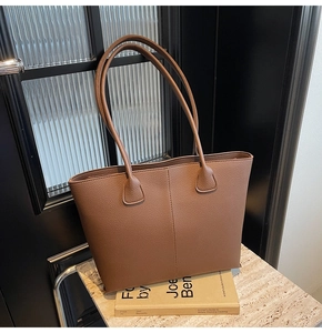 Macro view of dark brown lychee textured leather tote bag with elegant vertical stitching