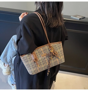 Detail der Hahnentritt-Tasche mit braunem Lederriemen und Goldplakette am Model