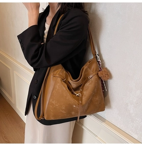 Brown leather large capacity shoulder bag shown with cute bear charm for daily commute