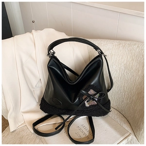 Detalle de bolso tote de cuero y borreguito con corazón de lentejuelas en sofá blanco