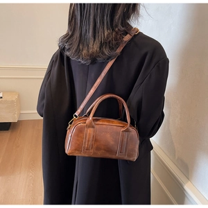 Detail of vintage brown leather handbag featuring vertical stitching and a brand logo