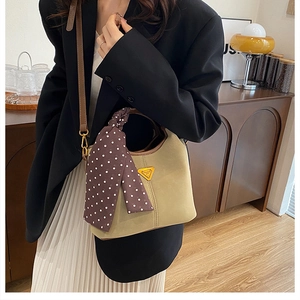 Détail du sac seau kaki en daim avec bordure en cuir marron et foulard à pois chic