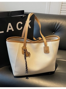Chic beige pebble leather tote bag with brown straps and elegant hanging charm detail