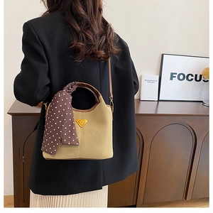 Détail du sac seau en daim beige avec anses marron et accessoire de foulard à pois chic
