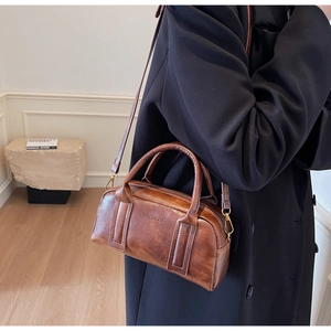 Brown vintage Boston bag with oil wax leather texture and logo detail shown on model