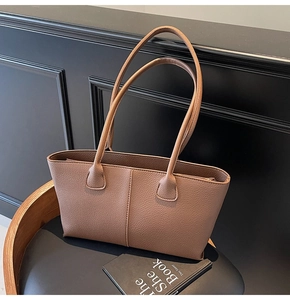 Close-up of brown litchi grain leather tote bag with fine stitching and slim handles