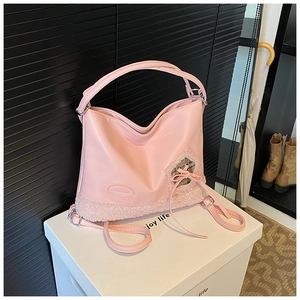 Detalle de bolso rosa de cuero sintético con ribete de borreguillo y lazo decorativo