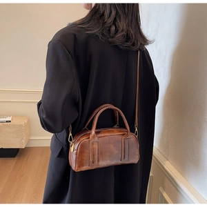 Deep brown retro Boston bag with top handles and logo detail shown on shoulder