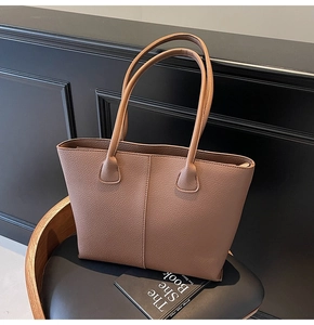 Detail of brown litchi pattern leather tote bag with vertical stitching and slim handles