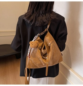 Brown faux leather crossbody bag with silk scarf and teddy bear charm on model