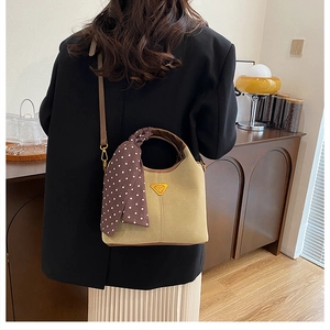 Sac seau moderne avec foulard à pois et bandoulière en cuir dans un décor intérieur