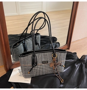 Detail der Hahnentritt-Tasche mit Lederlogo und dekorativem Tennisschläger-Anhänger