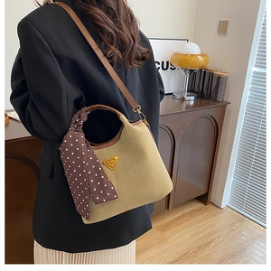 Détail du sac seau kaki avec logo triangle doré et foulard à pois sur la poignée