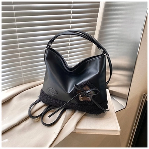 Detalle de bolso shopper negro en piel sintética con textura de lana y lazo elegante