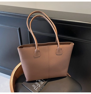 Close-up of brown pebbled leather tote bag with long straps on a black seat