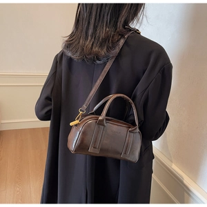 Detail of dark brown vintage pillow bag featuring golden hardware and embossed brand logo