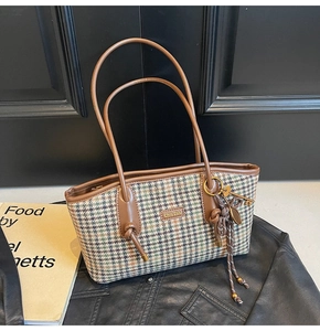 Detailansicht der Hahnentritt-Tasche mit braunem Lederbesatz und Logo-Plakette