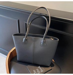 Detail of lychee textured black tote bag with reinforced handles on a vintage chair