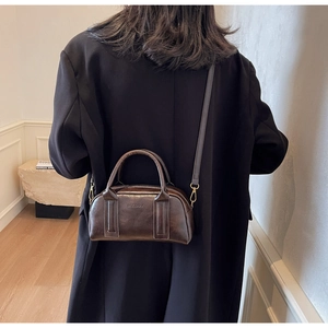 Detail of a dark brown vintage Boston bag showing premium leather texture and embossed logo