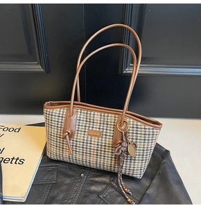 Detail der karierten Tweed-Schultertasche mit Lederbesatz und Goldakzenten auf Jacke
