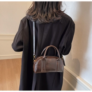 Detail of a dark brown vintage Boston bag showing the embossed logo and gold metal hardware