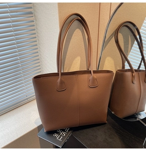 Close-up of brown litchi grain leather tote bag with vertical stitching detail