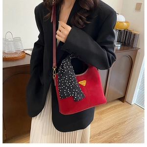 Détail du sac bandoulière rouge mat avec logo doré et foulard en soie à pois élégant