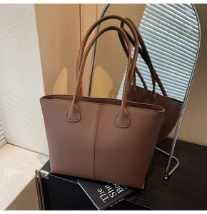 Close-up of deep brown tote bag with litchi grain texture and elegant vertical stitching