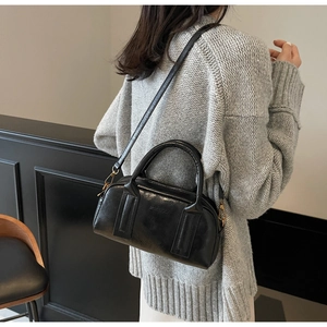 Close-up of black glossy Boston bag with reinforced handles and removable shoulder strap