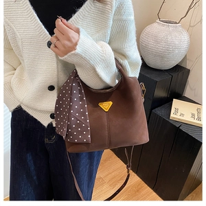 Détail d'un sac à main en daim marron foncé avec plaque dorée et foulard à pois chic
