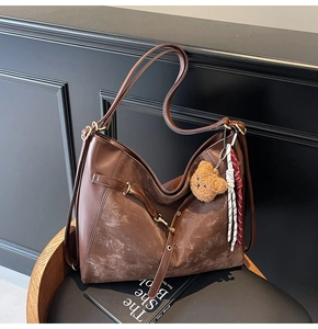 Close-up of brown PU leather shoulder bag with bear pendant and metallic buckle detail