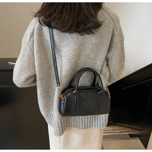 Detail of black Boston bag with embossed logo and elegant circular handles in use
